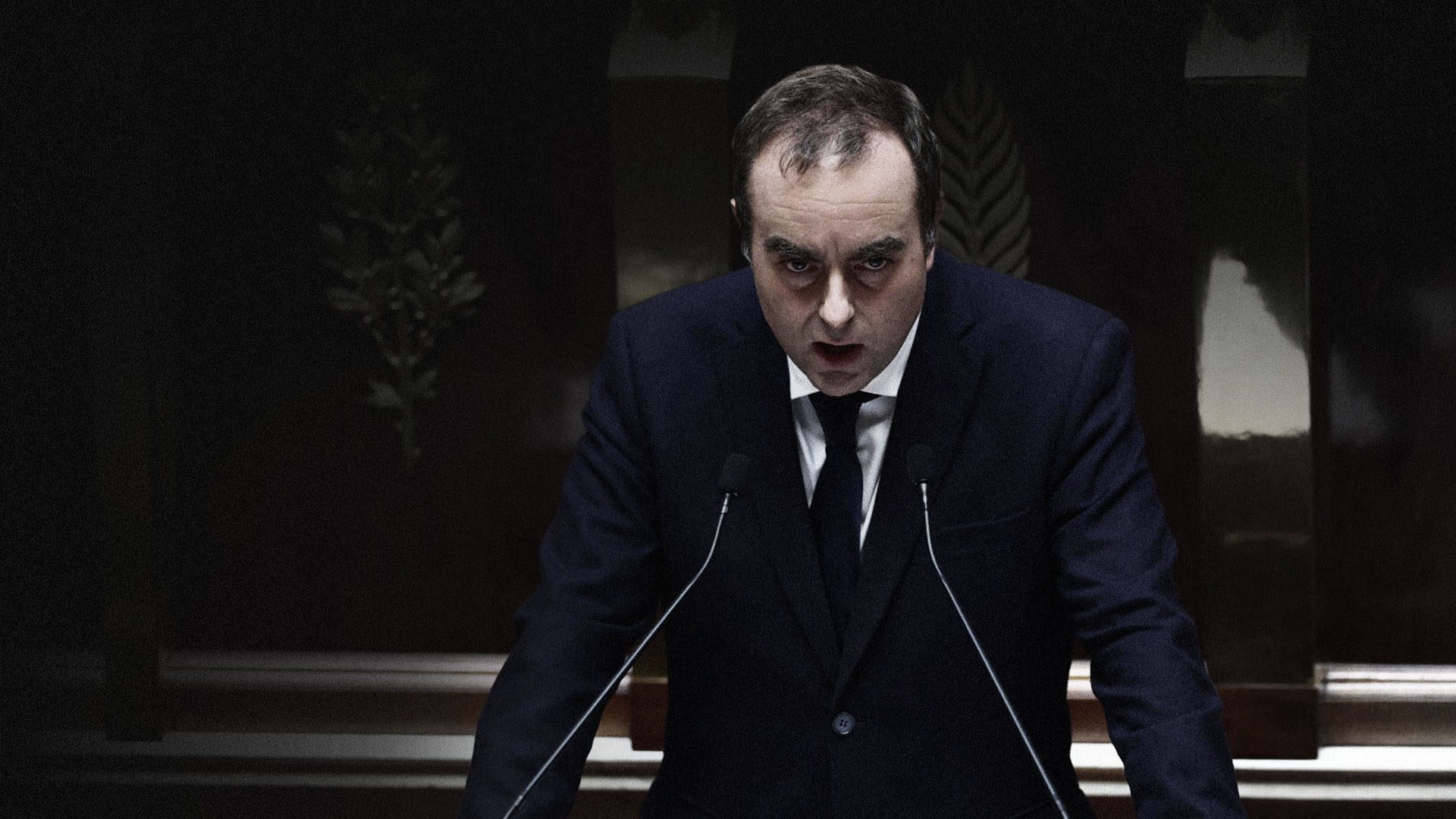 Lecornu-DPG Sébastien Lecornu, le Premier ministre, en costume sombre et cravate noire se tient à la tribune de l'Assemblée nationale, penché en avant, le regard intense et le visage sérieux. Il parle dans deux micros. En arrière-plan, des motifs végétaux dorés ornent un mur sombre.